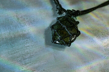 A striking labradorite pendant on a dark cord, showcasing its captivating flash on a textured...