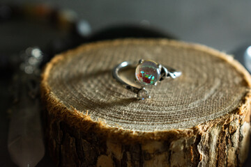 A mesmerizing moonstone ring with a captivating play of light, displayed elegantly on a rustic wooden slice. Perfect for themes of unique jewelry, natural beauty, and mystical charm.