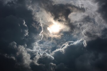 Sun glows through dark clouds in sky. Possible use dramatic or ominous backdrop