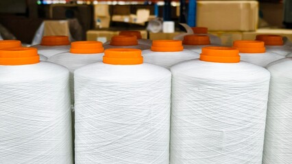 White spools of thread with orange caps in a factory