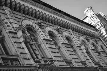 Facade of old historical grey stone building with with carved cornices, arched stone windows,...
