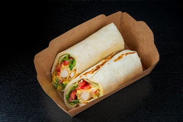 Two mouthwatering chicken wraps are presented in a simple container, perfect for a satisfying meal