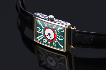 Luxury designer wristwatch featuring a green rectangular dial, white exaggerated numerals, and a...