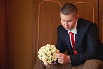 A woman in a wedding dress is sitting on a chair and putting on her white stockings. Concept of...