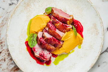 Savor the exquisite flavors of duck breast drizzled with berry sauce, nestled on squash puree