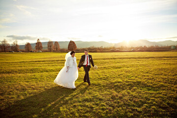A man and woman are sitting on a bench, the man is wearing a suit and the woman is wearing a white...