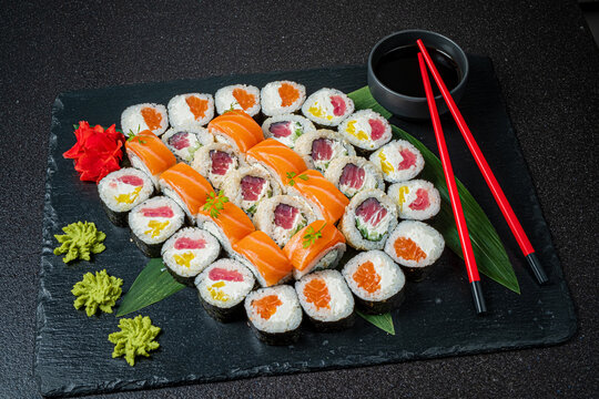 Naklejki Artfully arranged sushi rolls displayed on a dark slate board, ready to enjoy