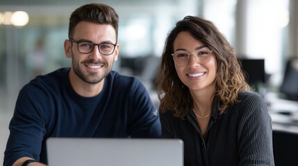 Young caucasian professionals smiling at office desk with laptop.