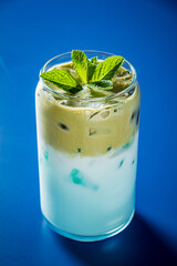 Creamy layers blend with rich coffee atop mint leaves, creating a refreshing beverage delight