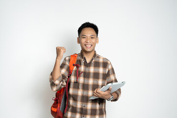 A cheerful young student with a tablet and backpack poses in casual attire against a plain...