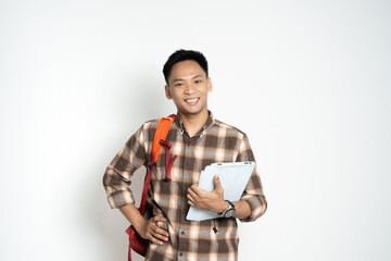 A cheerful young student with a tablet and backpack poses in casual attire against a plain...
