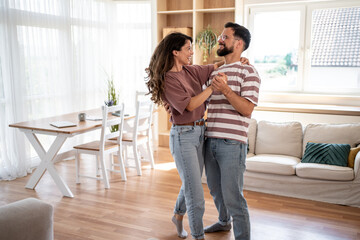 Happy couple dancing together in their modern living room