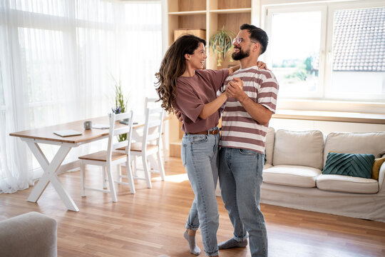 Happy couple dancing together in their modern living room - Powered by Adobe