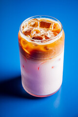 Creamy iced coffee meets milk with a refreshing sensation against a bold blue background