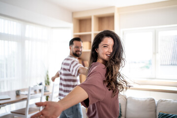 Happy couple holding hands and spinning around in living room