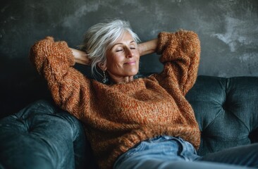 Relaxed senior woman with silver hair enjoys peaceful moment on comfy couch.