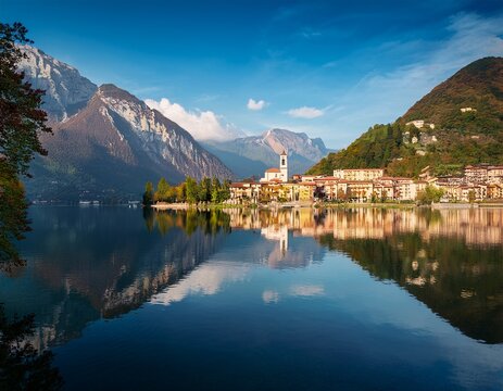 scenic view of mountains and village reflected in lago di annone italy