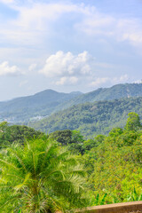 Naklejka premium Views through lush green trees and palms over looking Kata and Kata Noi on the beautiful island of phuket in Thailand with lush green mountains and turquoise blue waters of the Andaman Sea