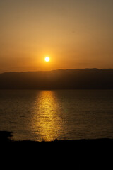 Obraz premium Golden Sunset over the Dead Sea with Mountain Silhouette and Water Reflection