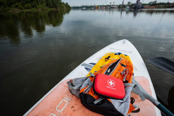 A bright red first aid kit is securely placed on a paddle board, ensuring quick and easy access for...