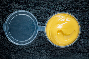 Smooth and vibrant cheese spread shines in a clear container, ready for tasty snacks and meals