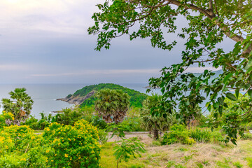 Sunset at Promthep Cape overlooking Nai Harn Beach and just off shore a small island Ko Man in the island of Phuket Thailand. Lush green trees and turquoise waters of the Andaman Sea