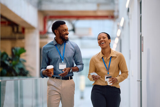 Cheerful black coworkers talking while having coffee break in office.