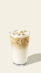 Iced coffee beverage in a clear glass with ice cubes and creamy foam on top, presented against a soft neutral background, showcasing refreshing drink appeal