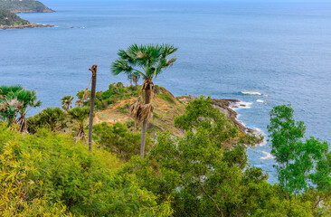 Sunset at Promthep Cape overlooking Nai Harn Beach and just off shore a small island Ko Man in the island of Phuket Thailand. Lush green trees and turquoise waters of the Andaman Sea