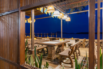 Blue skies at Blue hour Sunset over Rawai Beach in Phuket island Thailand. Restaurants with colourful lanterns lighting up the footpath. Lovely turquoise blue waters, lush green trees and mountains 