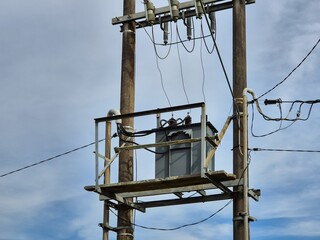 Rural Power Transformer Mounted on Utility Pole Under Blue Sky
