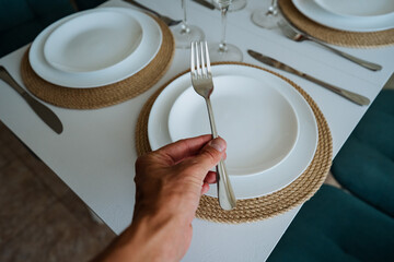 An individual expertly balances and holds a fork and spoon above a beautifully arranged plate that...