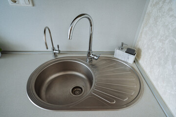 A beautifully designed stainless steel kitchen sink that features not one, but two faucets neatly...