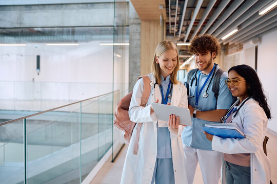 Group of happy medical and nursing students using digital tablet in hallway. - Powered by Adobe
