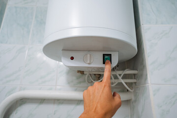 A person is actively pressing a button on a device that controls a bathroom water heater, which is...