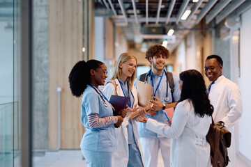 Happy medical students communicating in hallway at university hospital.