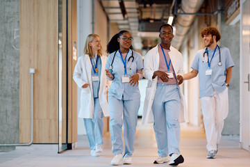Happy student doctors walking through hallway of university hospital.