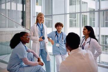 Happy student doctors talking while relaxing at university hospital hallway,