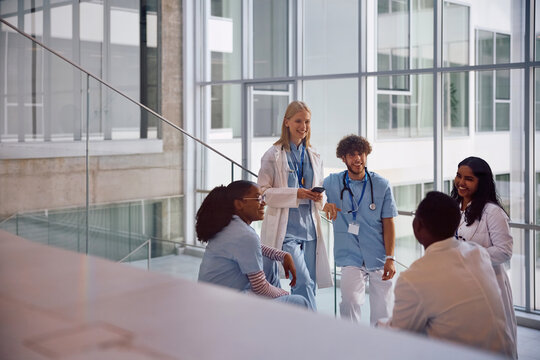 Happy diverse student doctors communicating in hallway at medical university.