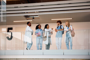 Multiracial group of student doctors communicating in hallway at university hospital.