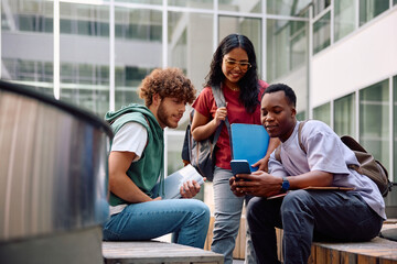 Multiracial group of college friends using smart phone at campus