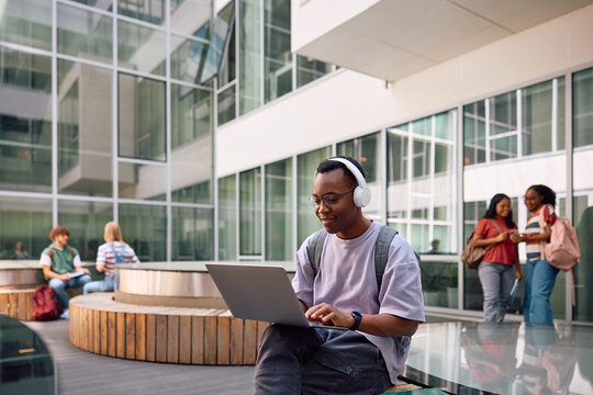 Happy black student surfing the net at university campus.