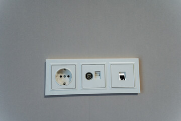 In this image, you can see a detailed closeup view of a white electrical outlet that is firmly...