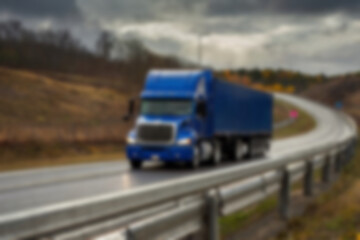 Blurry photo of container truck carrying large containers on highway with beautiful sunset.