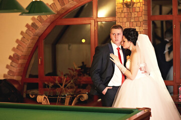 A man and woman are standing in front of a pool table