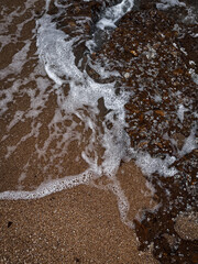 Sea waves crash against the rocky shore, creating white foam. Waves rocky shore.