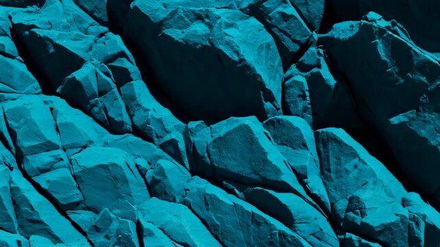 Extreme close-up of a jagged teal colored rock formation with sharp edges under hard light, camera slowly zooms in