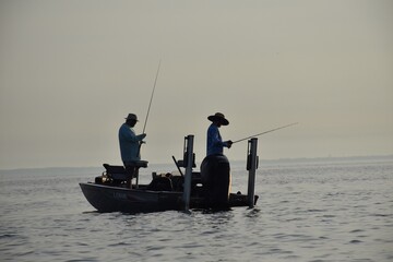 Angler fishing at sunrise in a boat