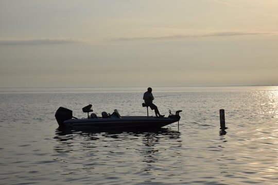 Angler fishing at sunrise in a boat - Powered by Adobe