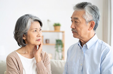 シニア夫婦が室内で向かい合い真剣に会話する様子｜シニア,夫婦,会話,高齢者,室内,白背景